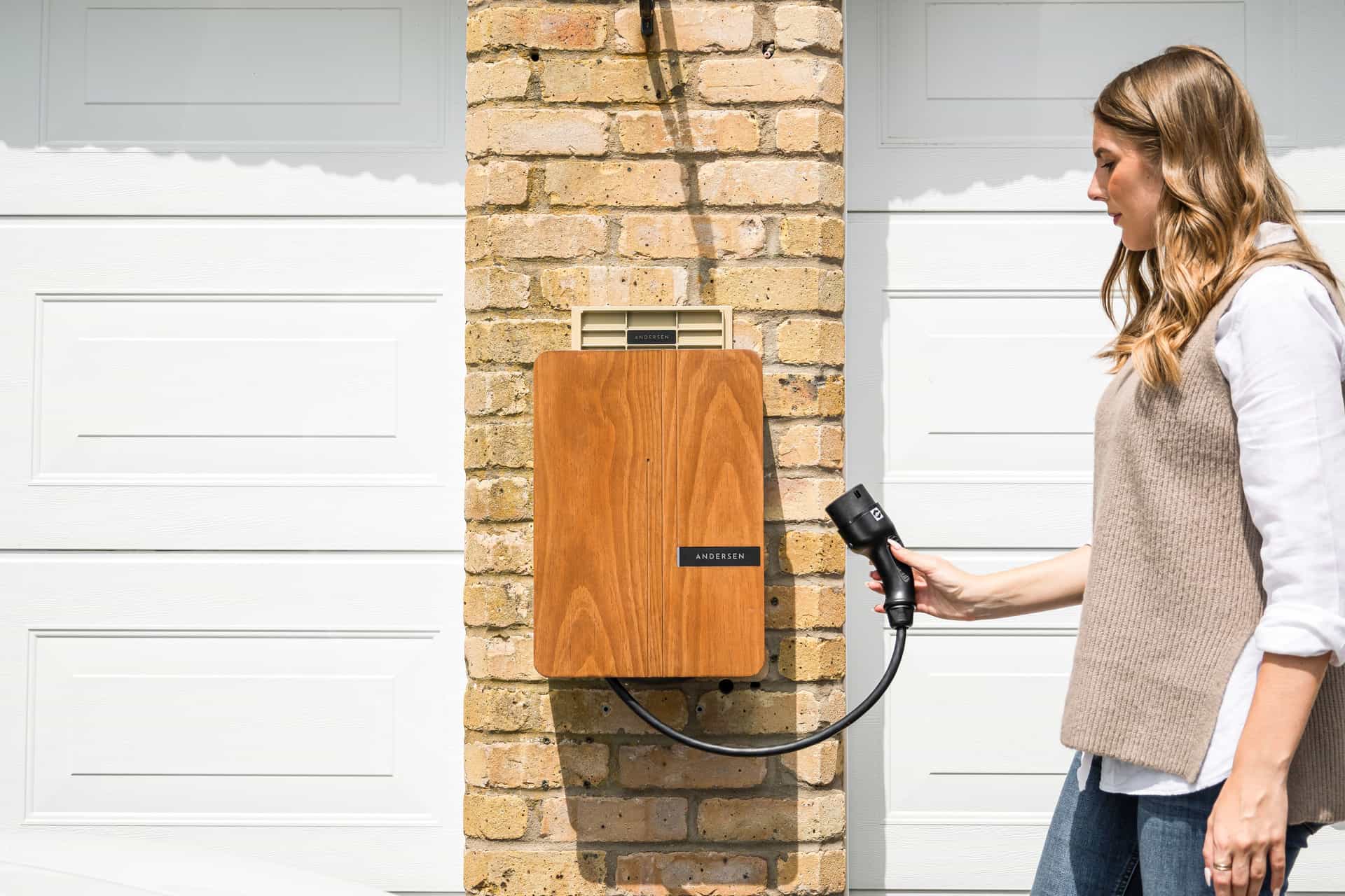 An electric car parked and plugged in to charge outside a modern home
