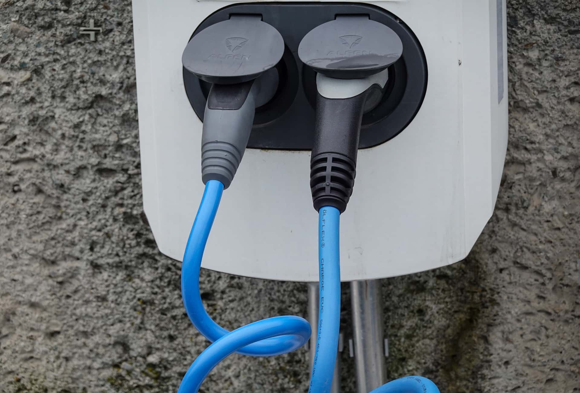 A coiled EV charging cable and connector on a light background